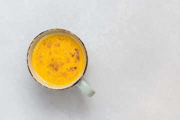 Turmeric latte with milk and cinnamon. Elixir of health and vivacity. Traditional healthy Indian detox drink. White background, top view, copy space