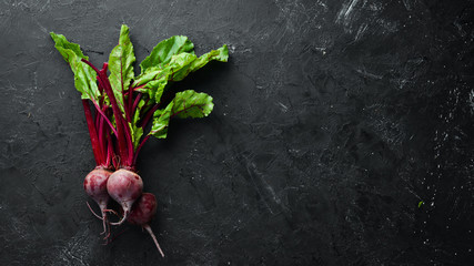 Fresh beetroot with leaves on a black stone background. Healthy food. Top view. Free space for your...