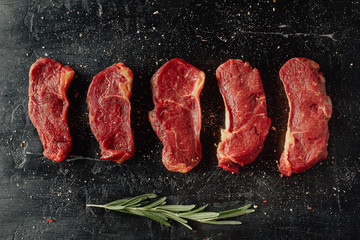 Beef background. Chopped beef steaks on a black table. Minimal closeup top view flat lay.