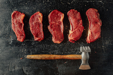 Beef background. Chopped beef steaks on a black table. Minimal closeup top view flat lay.