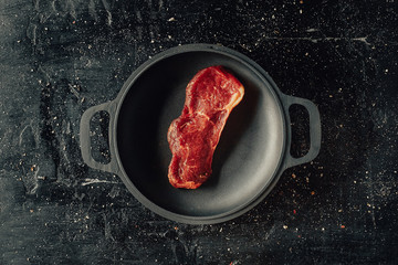 Raw beef steak on a frying pan, top view, flat lay, copyspace.