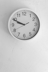 Time concept. White clock on a white grungy wall vertical image with place for text on the bottom part of the image.