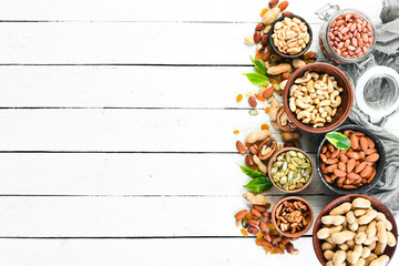 Assorted nuts on a white wooden background. Top view. Free space for your text.