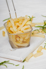 French fries with rosemary on a white wooden table in a basket closeup