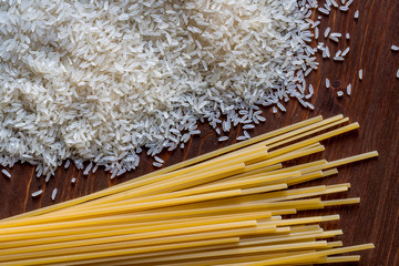 beam of pasta and  yellow raw dry rice on a colored brown background. Groats and makaroni on a wooden table.