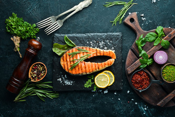 Grilled salmon steak on a stone plate. On an old background. Top view. Free copy space.