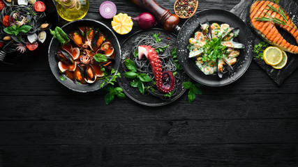 Set of Seafood Dishes. Seafood on a plate. On a black wooden background. Top view. Free copy space.