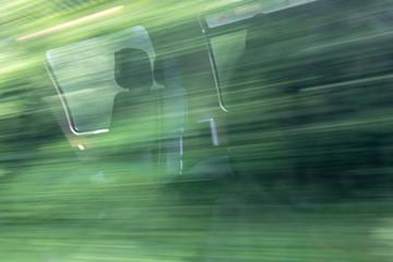 blurry abstract green landscape and seat reflections seen from train window in motion