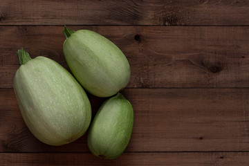 Three  fresh zucchini on a wooden background. Harvest season themes