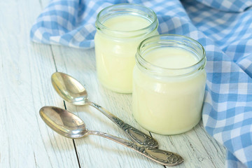 Greek yogurt in glass jars with spoons on a blue background. Healthy food concept.