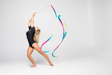 The portrait of beautiful young woman gymnast training calilisthenics exercise with ribbon on white...