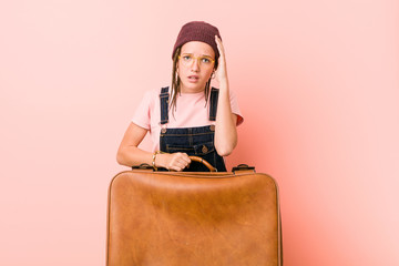 Young caucasian woman holding a suitcase being shocked, she has remembered important meeting.