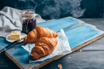 delicious croissants with jam on dark wooden table