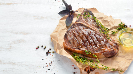 Medium rare Grilled T-Bone Steak on a white table. Top view. Free space for text.