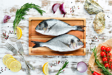 Raw fish with lemon and spices on a white background. Fish dorado. Top view. Free space for your text.