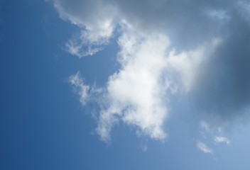 The sun and clouds on the blue sky. Cloudy weather with cumulus, dark clouds. Autumn day. A strong wind blows, the pressure is low, the threshold of rain.