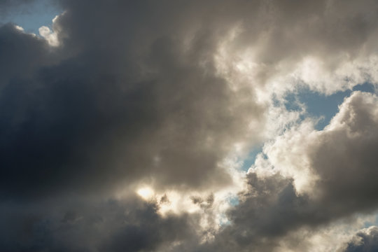 The sun and clouds on the blue sky. Cloudy weather with cumulus, dark clouds. Autumn day. A strong wind blows, the pressure is low, the threshold of rain.