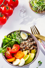 Fresh healthy salad with quinoa, cherry tomatoes and mixed greens, avocado, egg and micro greens on marble background top view. Food and health. Superfood meal. Clean eating. Healthy lifestyle