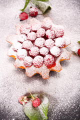 muffin decorated with fresh raspberries on a black plate.