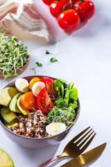 Fresh healthy salad with quinoa, cherry tomatoes and mixed greens, avocado, egg and micro greens on marble background top view. Food and health. Superfood meal. Clean eating. Healthy lifestyle