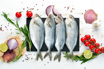 Raw fish with lemon, salt and rosemary. On a white wooden background. Top view. Free copy space.
