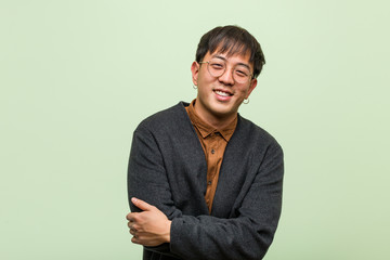 Young chinese man wearing a cool clothes style against a green background