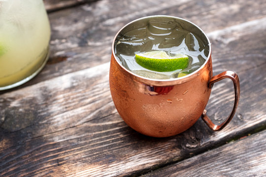 A Moscow Mule in a copper mug on an old wooden table on a summer day.