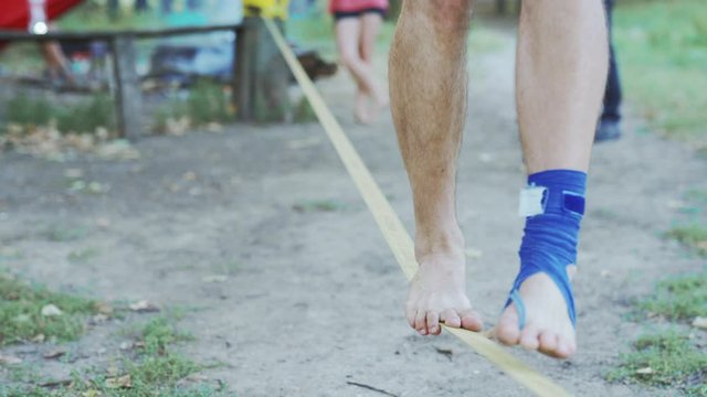 Man Feet On Slack Line Tight Rope. Balancing on a slack line. CLOSE UP: Unrecognizable Man slacking and balancing on a slackline, 4k stock footage