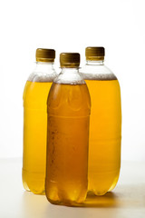 foamy beer in three transparent plastic bottles on a white background