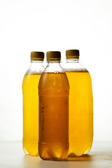 foamy beer in three transparent plastic bottles on a white background