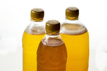foamy beer in three transparent plastic bottles on a white background
