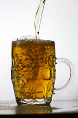 foamy beer in a transparent glass on a white background
