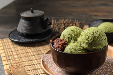 The homemade matcha ( Japanese green tea ) ice cream with red bean in the wooden bowl and put on bamboo mat.