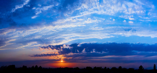 Fototapeta na wymiar Bright sunlight through the clouds against a breathtaking evening sky at sunset. panorama, natural composition