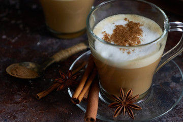 two hot cappuccino coffee with foam ,cinnamon , sugar and anise on a brown background