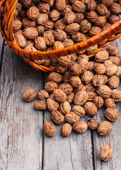 Walnuts in a wicker basket on a wooden background. Close-up