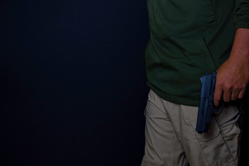 asian man holds a gun. Gun in his hand isolated on black background.