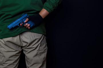 asian man holds a gun. Gun in his hand isolated on black background.