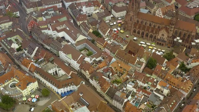 Aerial view of the old town of Freiburg in Germany on a cloudy day in summer. Pan to the right beside the church.