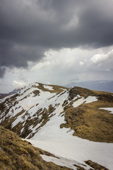 Dramatic, moody view from a Midzor summit, the highest peak of Old mountain, during transition period between winter and spring with some remaining snow and sunlit highlands