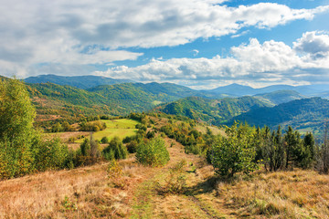 Fototapeta na wymiar beautiful mountain landscape in autumn. colorful scenery on a sunny day. changing weather with clouds on the sky. abandoned footpath down the hill. distant ridge in haze. travel back country concept