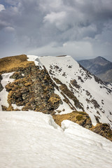 Dramatic, moody view from a Midzor summit, the highest peak of Old mountain, during transition period between winter and spring with some remaining snow and sunlit highlands