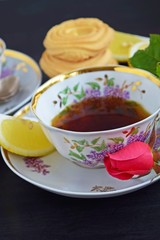 Fresh fragrant tea with lemon in a beautiful Cup on a black background.