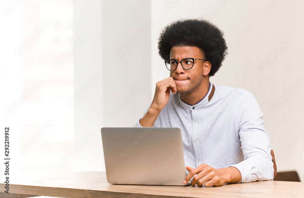 Wall mural young black man using his laptop thinking about an idea