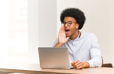 Young black man using his laptop whispering gossip undertone