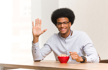 Fototapeta na wymiar Young black man having a breakfast showing number five