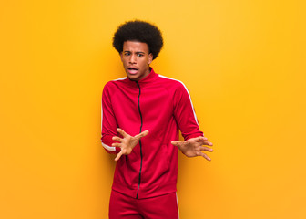 Young sport black man over an orange wall rejecting something doing a gesture of disgust