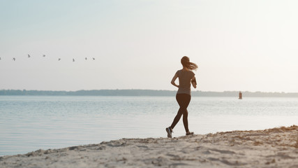 Female runner making workout on the beach in morning