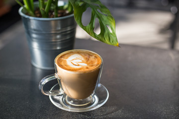 Cappuccino cup in coffee shop. Coffee with pot on black table. Latte with art for breakfast. Cafe culture.