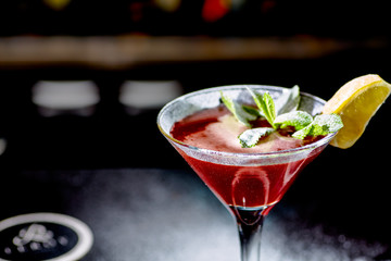 Red cocktail similar to a Margarita covered with powdered sugar is on the bar.